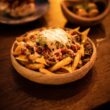 a wooden table topped with a bowl of fries