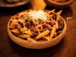 a wooden table topped with a bowl of fries