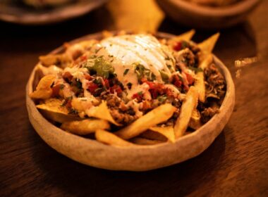 a wooden table topped with a bowl of fries