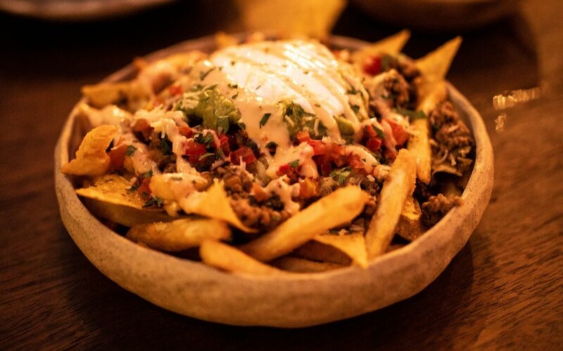 a wooden table topped with a bowl of fries