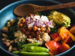 a blue bowl filled with vegetables and a wooden spoon